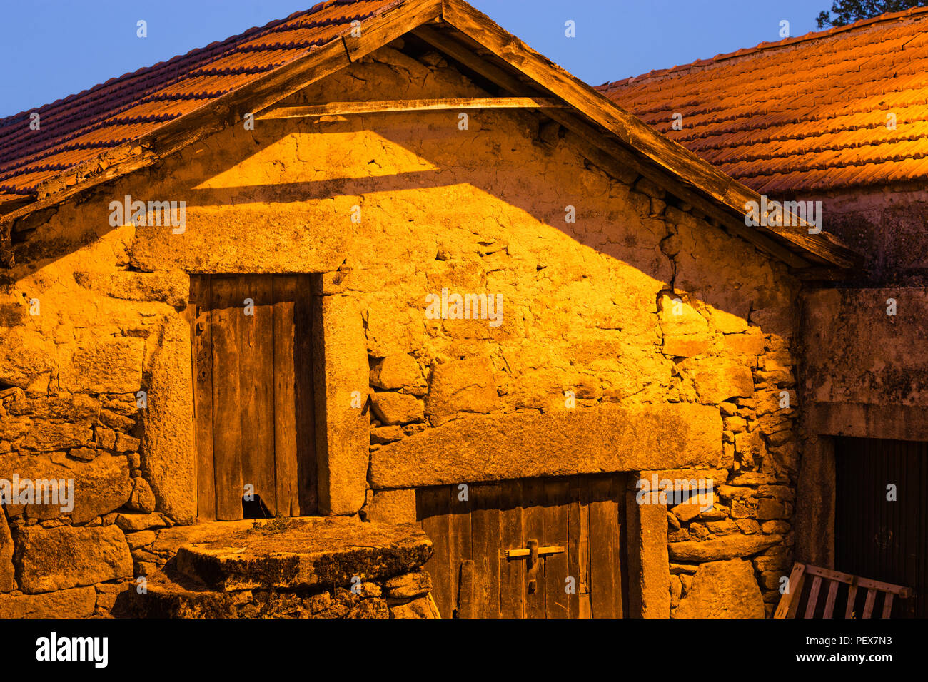 Serata di scena del villaggio con la tradizionale casa sotto le luci del villaggio di colata bagliore arancione, das Pitoes Junias, Alto Tras os Montes e Norte, Portogallo. Foto Stock