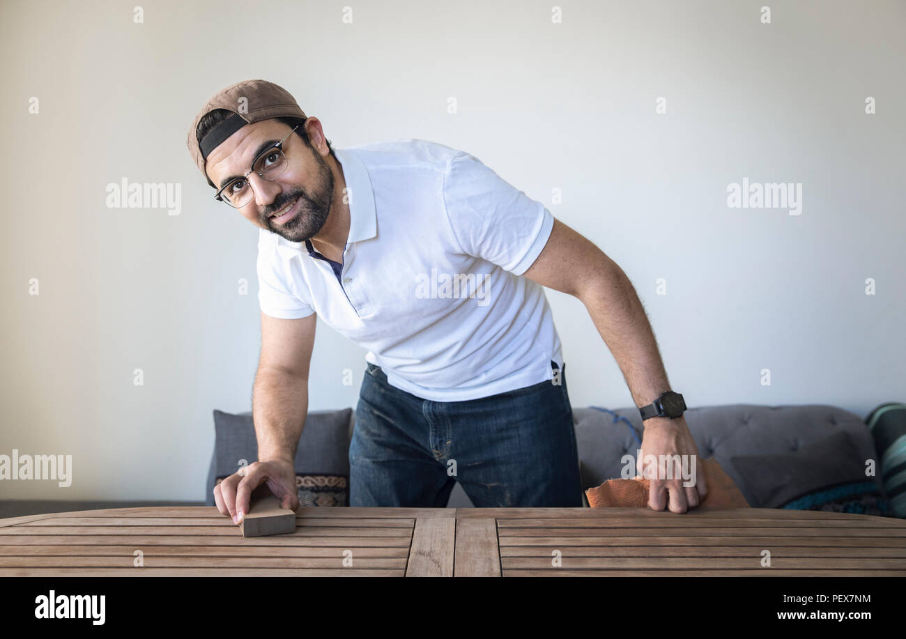 Uomo arabo giù di levigatura della superficie di un tavolo in teak Foto Stock