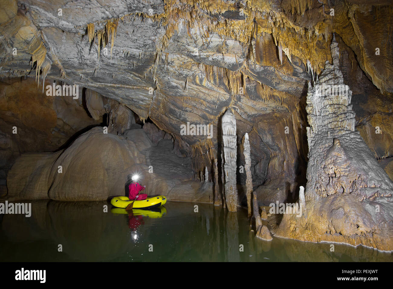 Un uomo ad esplorare il Krizna Jama grotta in barca. Regione carsica, Slovenia. Foto Stock