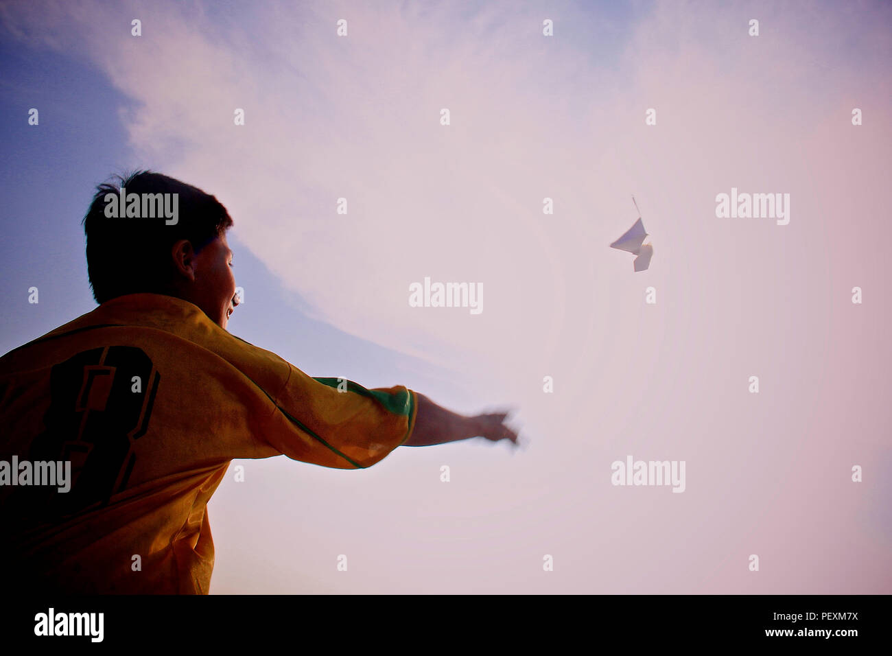 Ragazzo gettando aeroplano di carta nel cielo Foto Stock