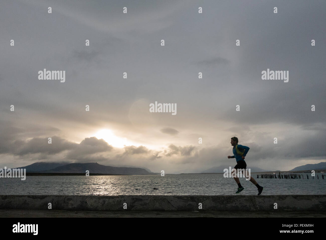 Uomo che corre lungo la costa, Puerto Natales, regione di Magallanes, Cile Foto Stock
