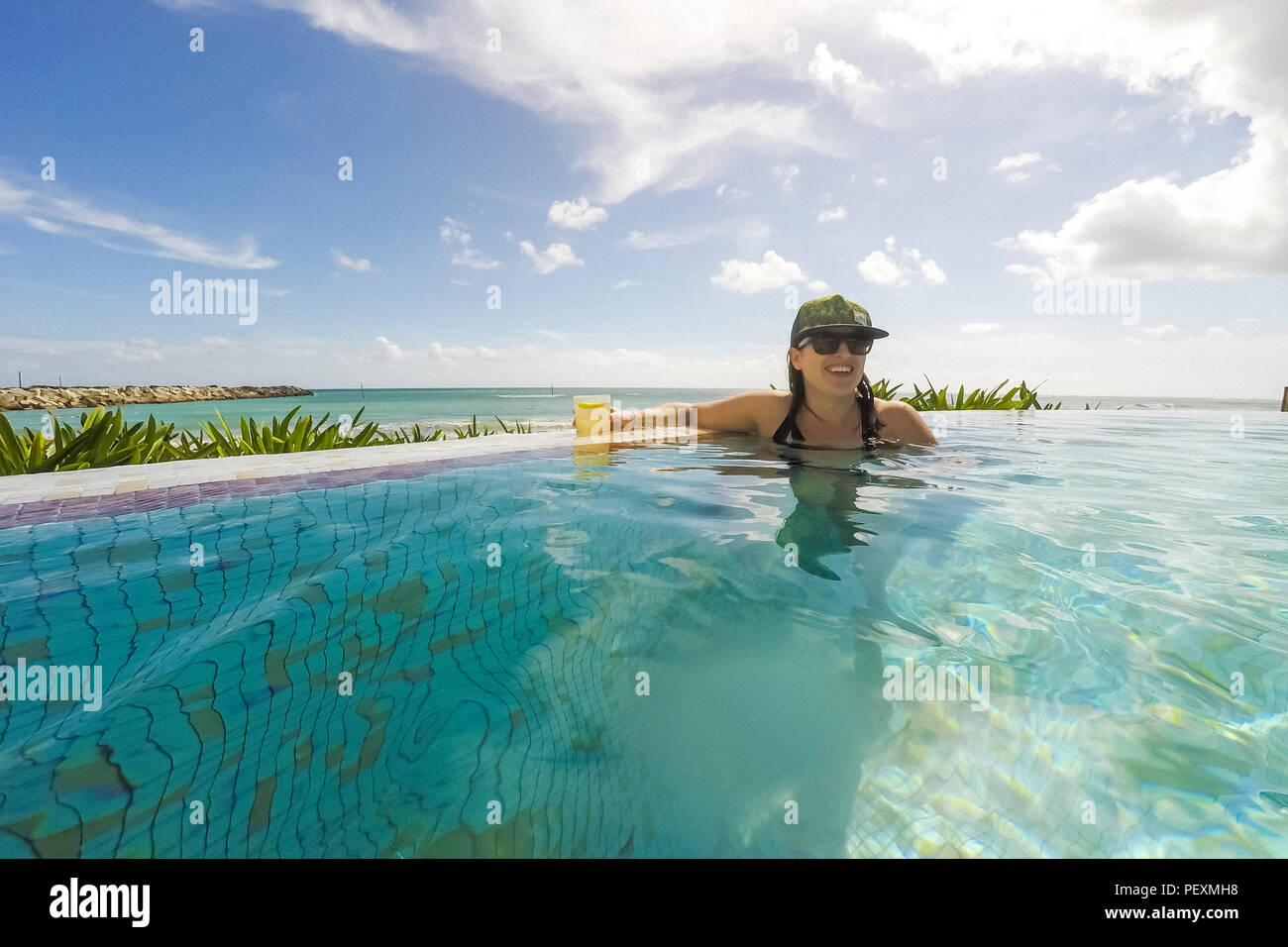 Donna di nuoto in Oceanside piscina con cocktail Foto Stock