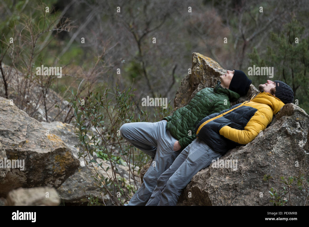 Due uomini che giace contro il rock e guardando in alto Foto Stock