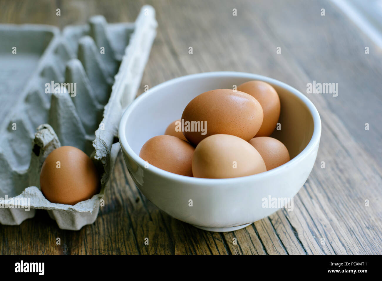 Di uova fresche in una terrina con un vicino astuccio vuoto Foto Stock