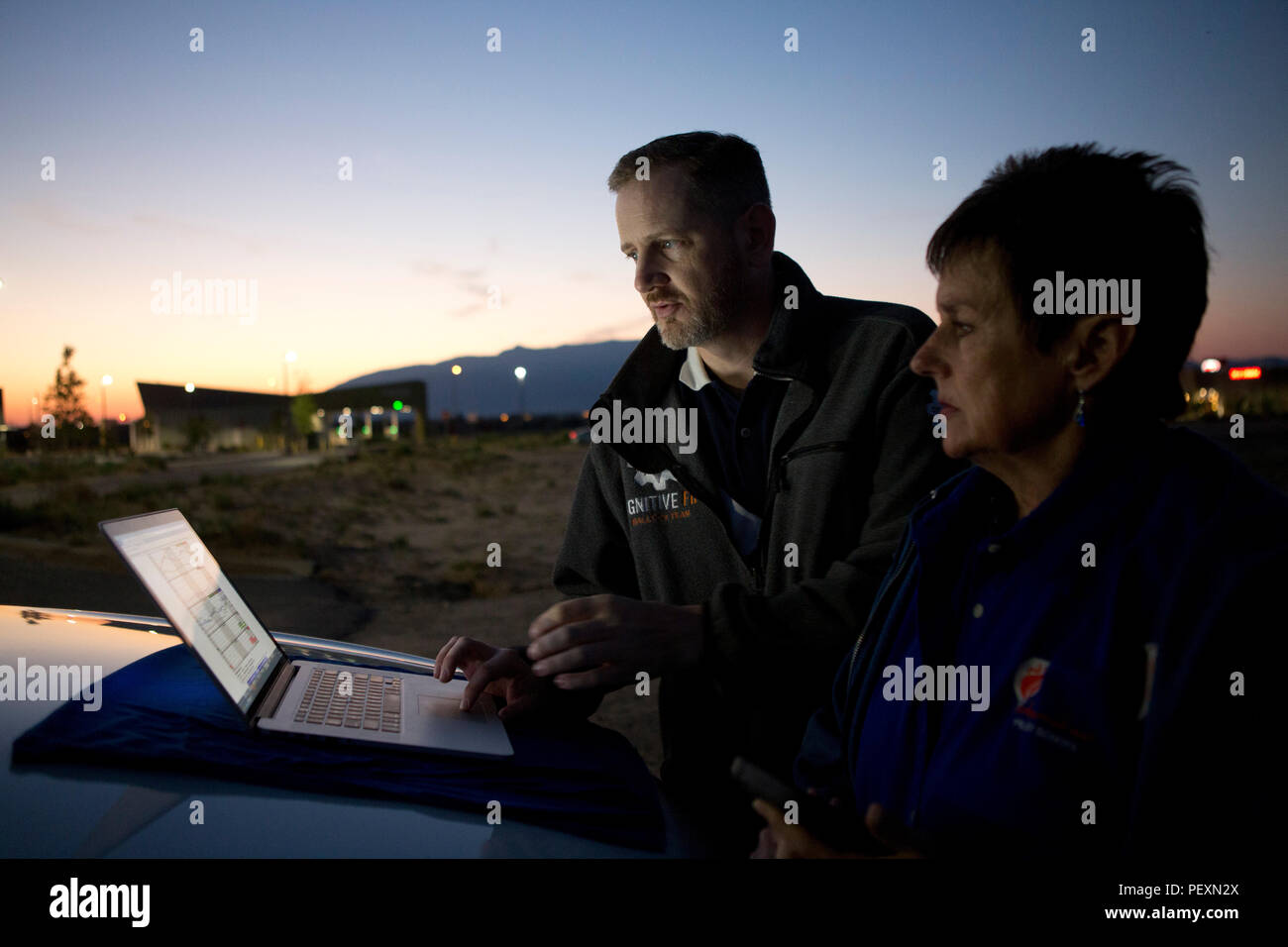 Uomo e donna che utilizza computer portatile al tramonto mentre si prepara per la mongolfiera lancio di Albuquerque, Nuovo Messico, STATI UNITI D'AMERICA Foto Stock