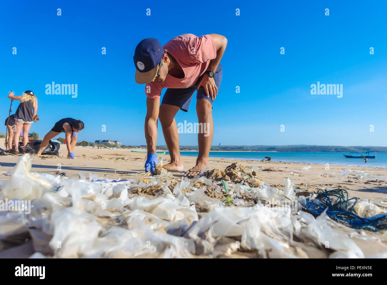 Man picking up trash presso la spiaggia di Jimbaran, Bali, Indonesia Foto Stock