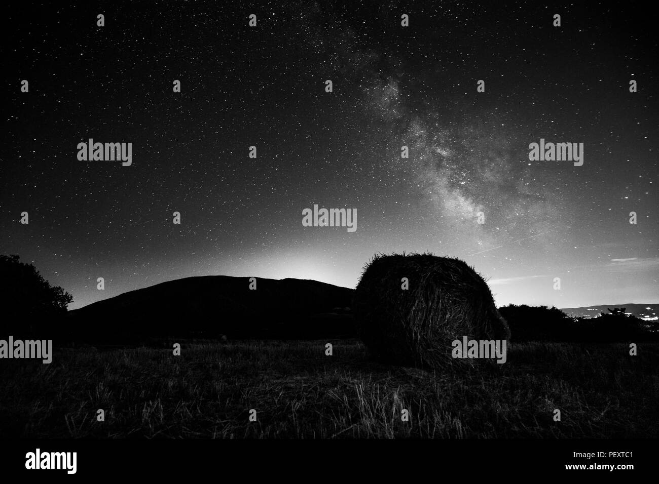 Bellissima vista starred il cielo notturno con via lattea su un campo coltivato con balle di fieno Foto Stock