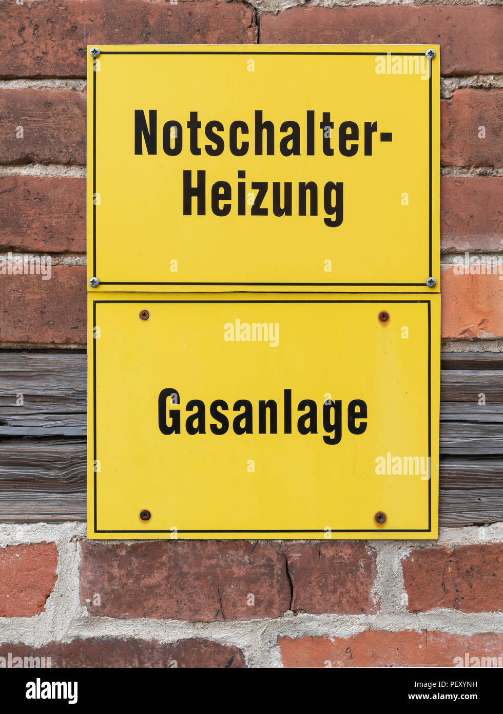 Due segni di colore giallo al di sotto di ogni altro con il tedesco iscrizioni Notschalter Heizung significa 'l'interruttore di emergenza riscaldamento' e Gasanlage significa "sistema gas' Foto Stock