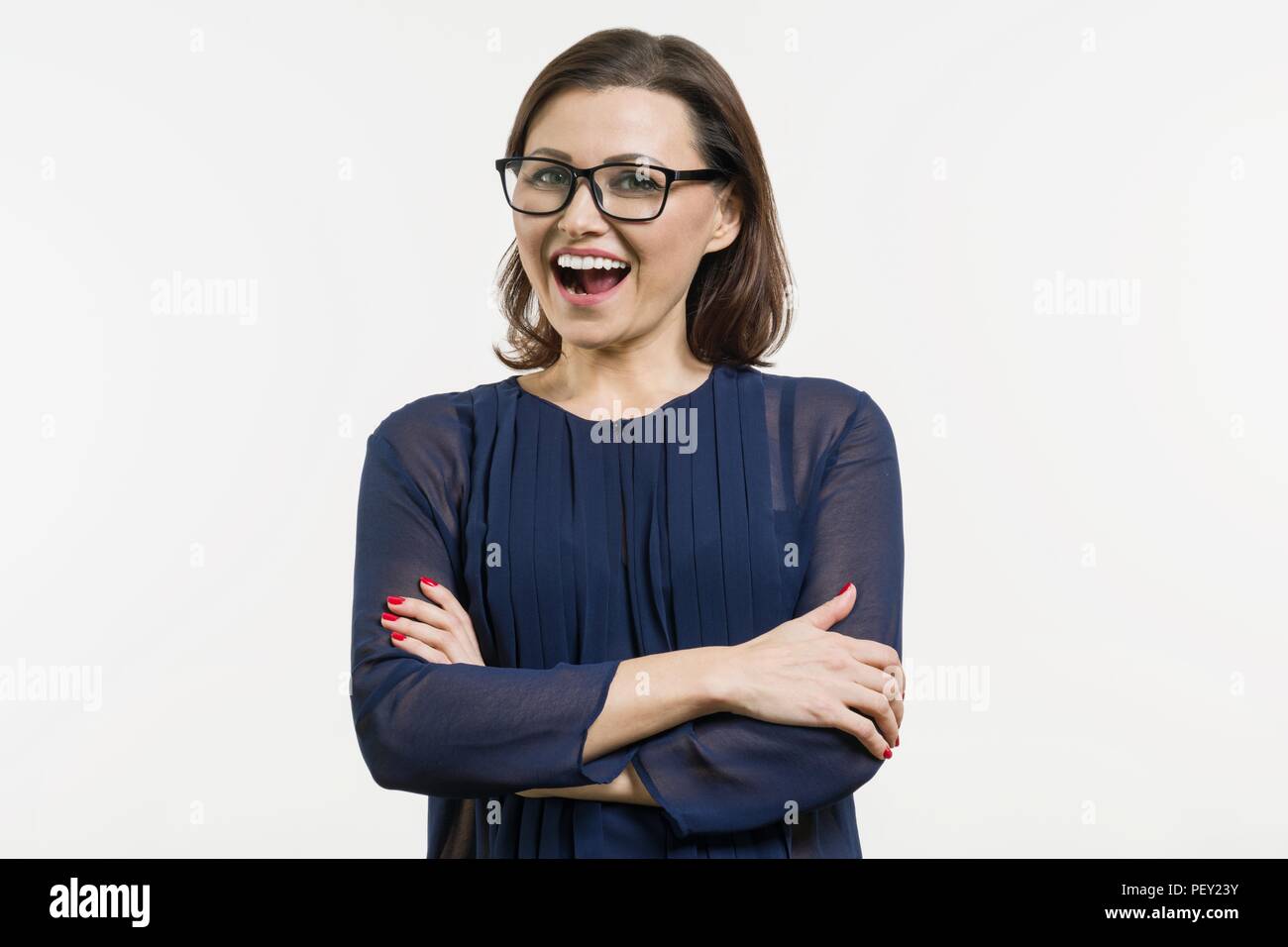 Sorridente donna di mezza età con bracci ripiegati su sfondo bianco. Foto Stock