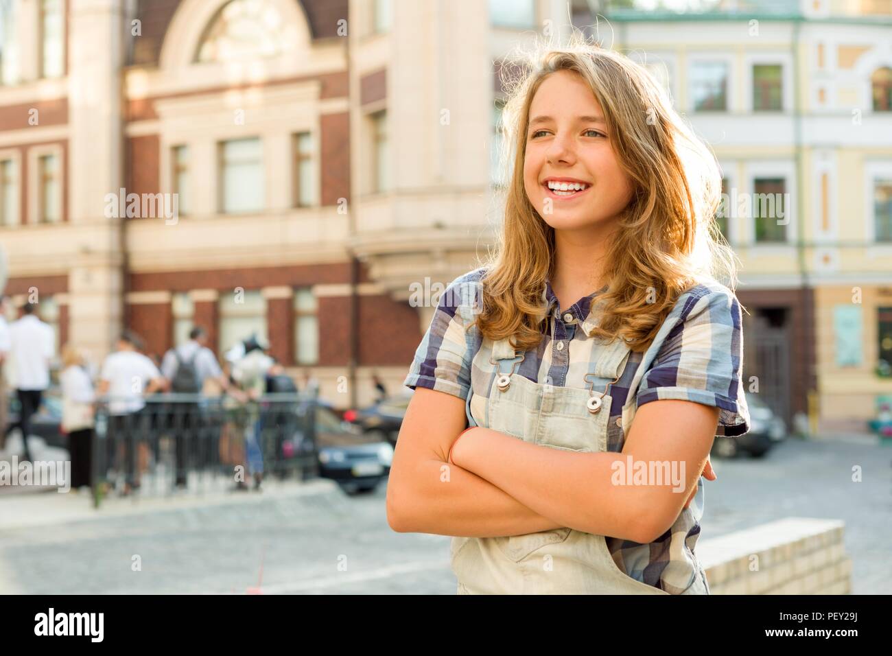 Outdoor ritratto di adolescente di 13, 14 anni, ragazza con bracci incrociati, strada di città sullo sfondo. Foto Stock