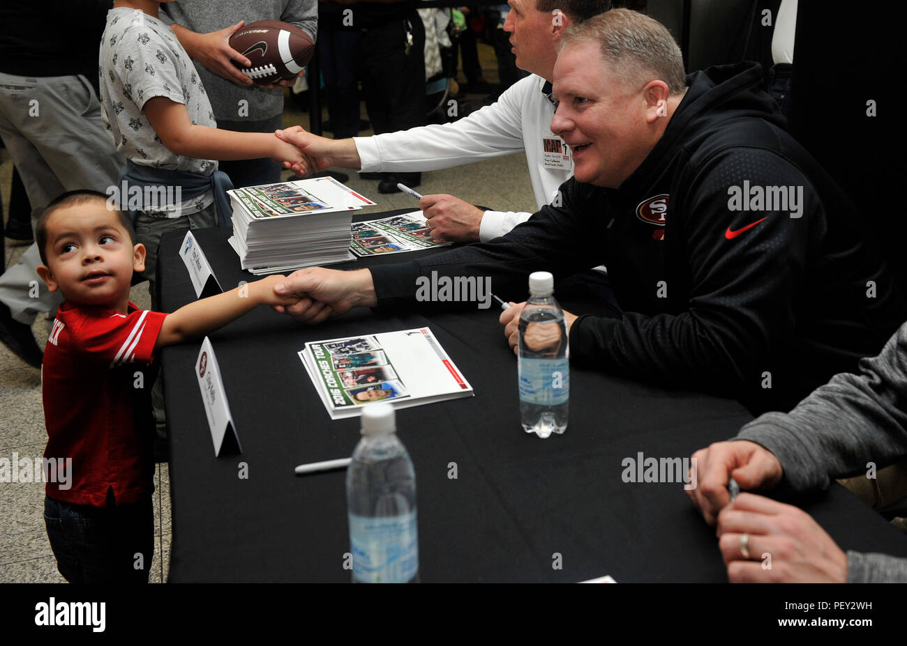 Chip Kelly, San Francisco 49ers head coach, scuote le mani con un giovane ventola durante un incontrare e salutare per il 2016 Pullman Tour di Febbraio 14, 2016 a Ramstein Air Base, Germania. Appassionati hanno avuto la possibilità di incontrare e parlare con e ottenere autografi da quattro pullman da entrambi la collegiata e le leghe professionistiche. (U.S. Air Force foto/Airman 1. Classe Larissa Greatwood) Foto Stock