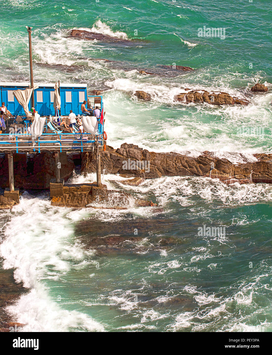 GENOVA, Italia : Persone rilassarsi e prendere il sole in un piccolo stabilimento bagno con cabine hanging off la scogliera Foto Stock