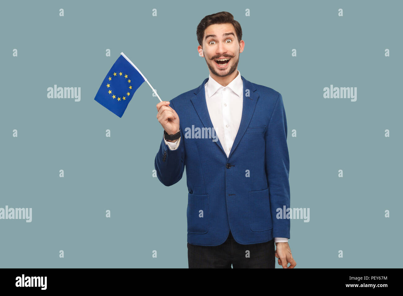Tempo per l'Europa. Bello stupiti businessman in giacca blu e camicia bianca tenendo bandiera dell'Unione europea e guardando con Fotocamera si chiedeva il volto. Indo Foto Stock
