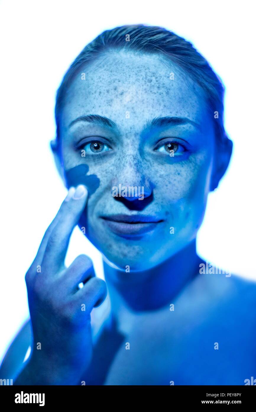 Donna l'applicazione di crema solare alla sua guancia. Foto Stock