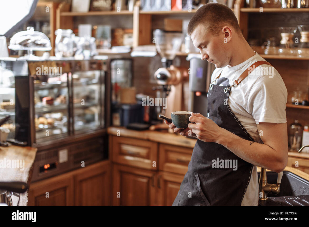 Bello il barista di bere il caffè e i messaggi di testo messaggio in smart phone. concetto di comunicazione Foto Stock
