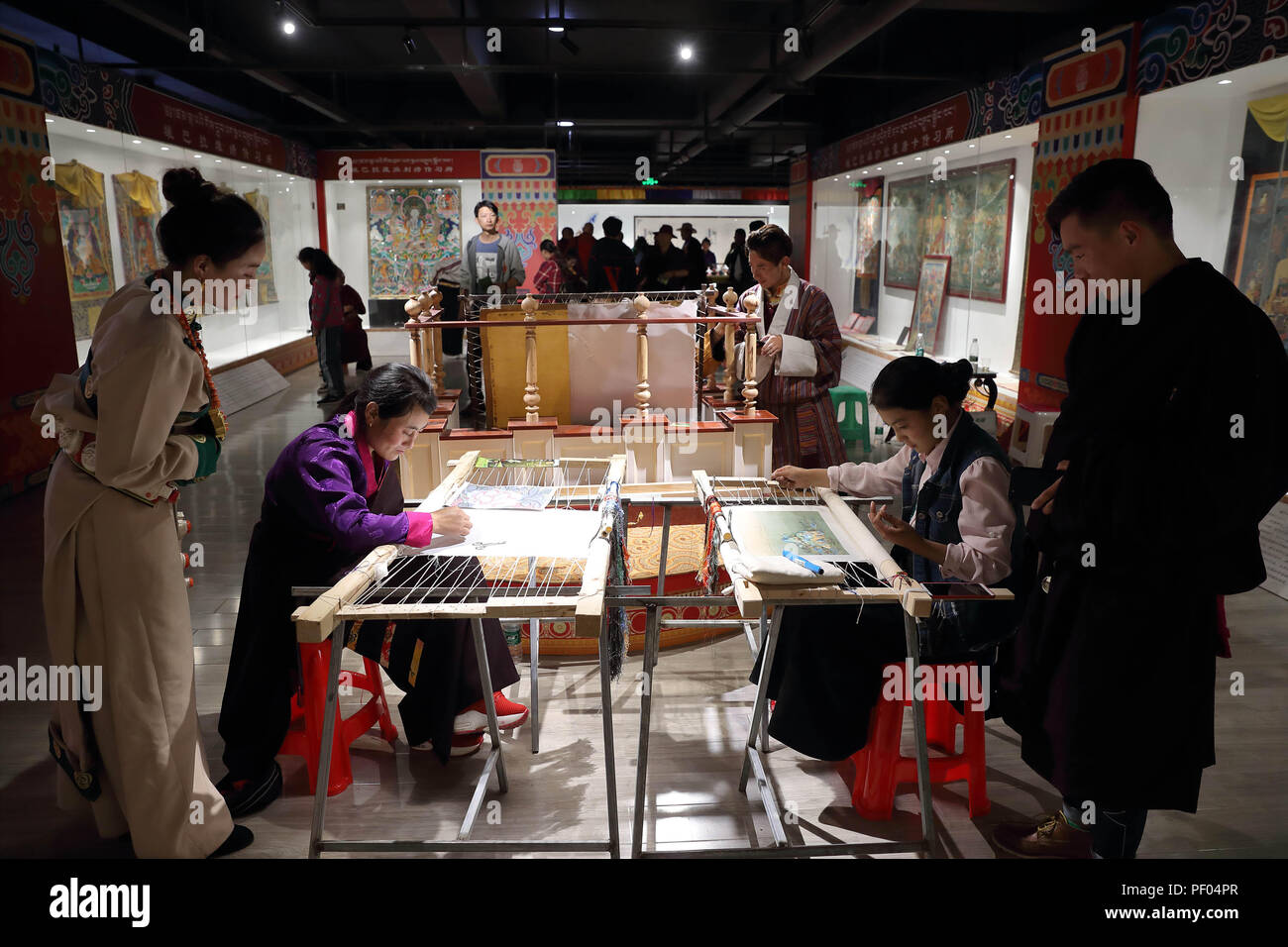 Rangtang, cinese della provincia di Sichuan. 17 Ago, 2018. Visitatori vista artisti folk rendendo ricami tibetani in un mercato di circa immateriali patrimoni culturali in Rangtang County, a sud-ovest della Cina di provincia di Sichuan, Agosto 17, 2018. Un mercato denominato mercato Rangbala, aperto al pubblico qui il venerdì, la presentazione e la vendita di prodotti su 26 tipi di locale immateriali patrimoni culturali. Credito: Jiang Hongjing/Xinhua/Alamy Live News Foto Stock