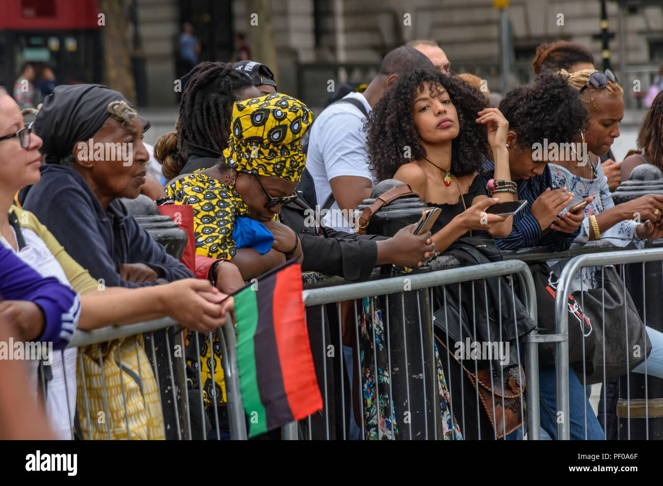 Londra, Regno Unito. Il 18 agosto 2018. Una persona davanti al pubblico detiene una bandiera panafricano all annuale National Memorial evento in Trafalgar Square per ricordare e onorare le vittime dell'Olocausto africano/Tratta degli Schiavi Transatlantica e promuove a livello internazionale la schiavitù Giorno del Ricordo, 23 agosto. L'evento chiamato per gli africani per celebrare la loro identità e per ricordare i loro antenati, e iniziò con libagioni ricordando molti eroi nero. ers ta Credito: Peter Marshall / Alamy Live News Foto Stock