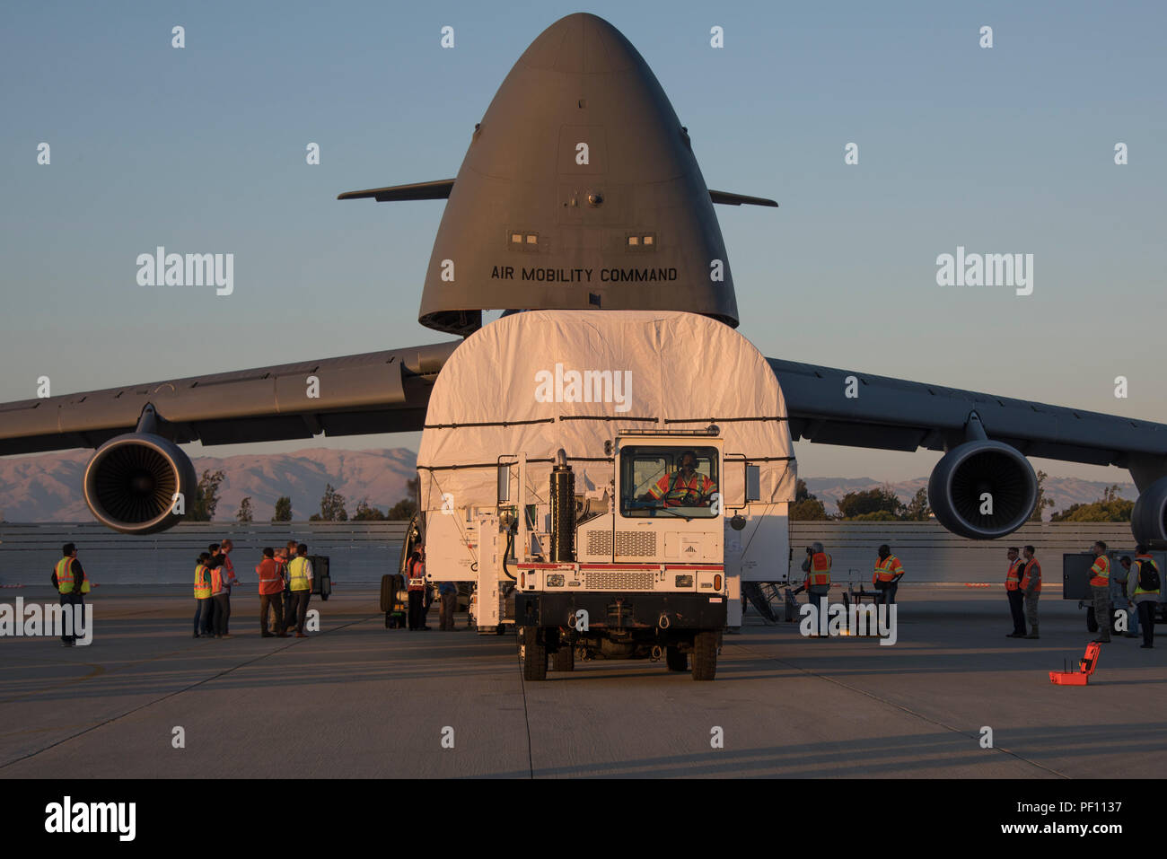Un trasportatore specializzato caricato con un sistema avanzato di frequenza estremamente elevata in-4 satellite di comunicazione viene guidato con precisione il carico in avanti Posizione di carico di un Travis Air Force Base C-5M Super Galaxy per trasporto, luglio 26, 2018,Sunnyvale, California Il satellite è stato trasportato alla Cape Canaveral Air Force Station, Florida. La costellazione AEHF è progettato per sostituire il Milstar costellazione di satelliti. (U.S. Air Force Foto di Heide lettino) Foto Stock