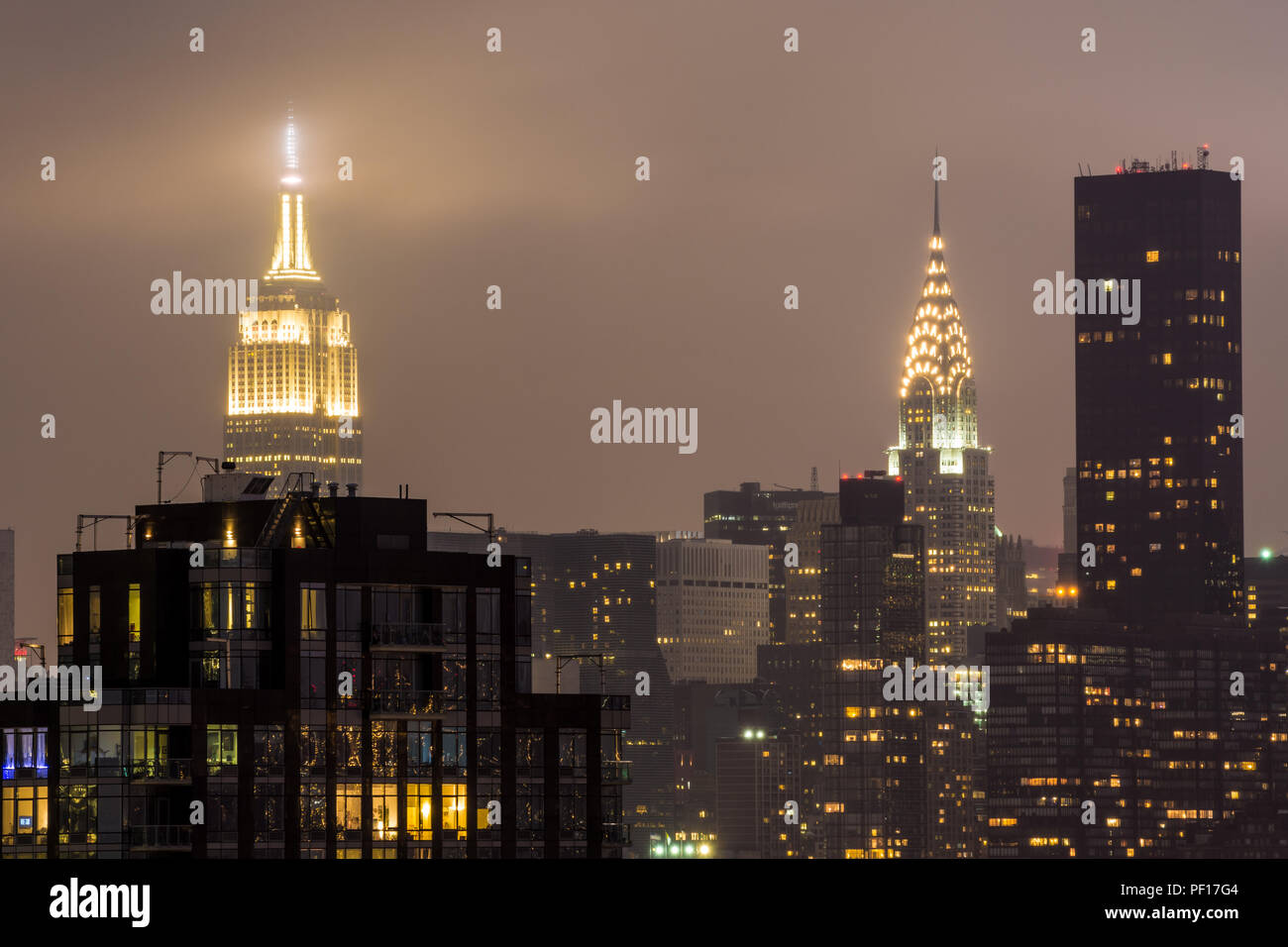 L'Empire State Building e il Chrysler Building illuminato di notte come visto dalla città di Long Island, Queens, a New York City. Foto Stock