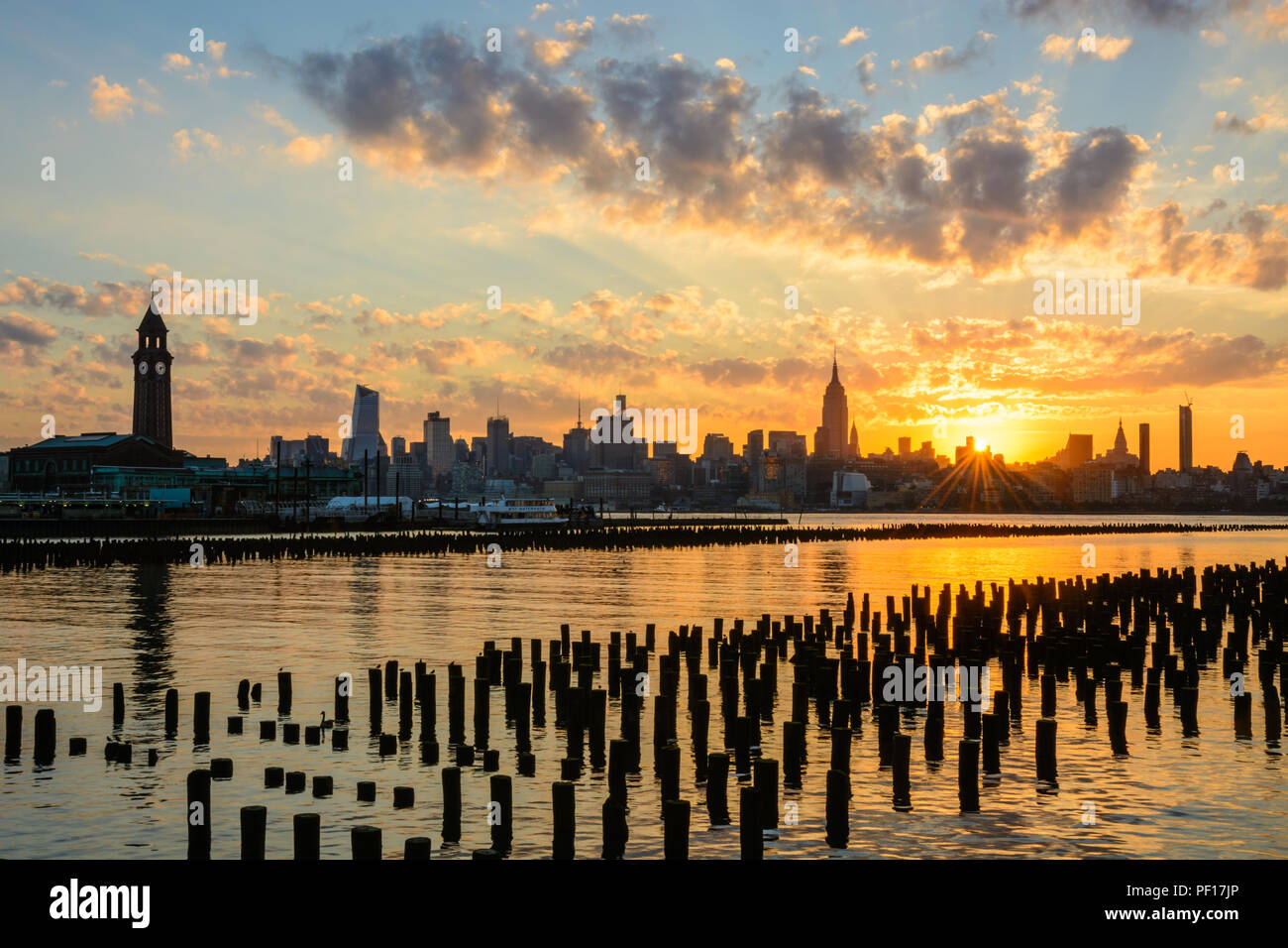 Il sole sorge oltre l'orizzonte di New York City come si vede dalla Hoboken, New Jersey waterfront. Foto Stock