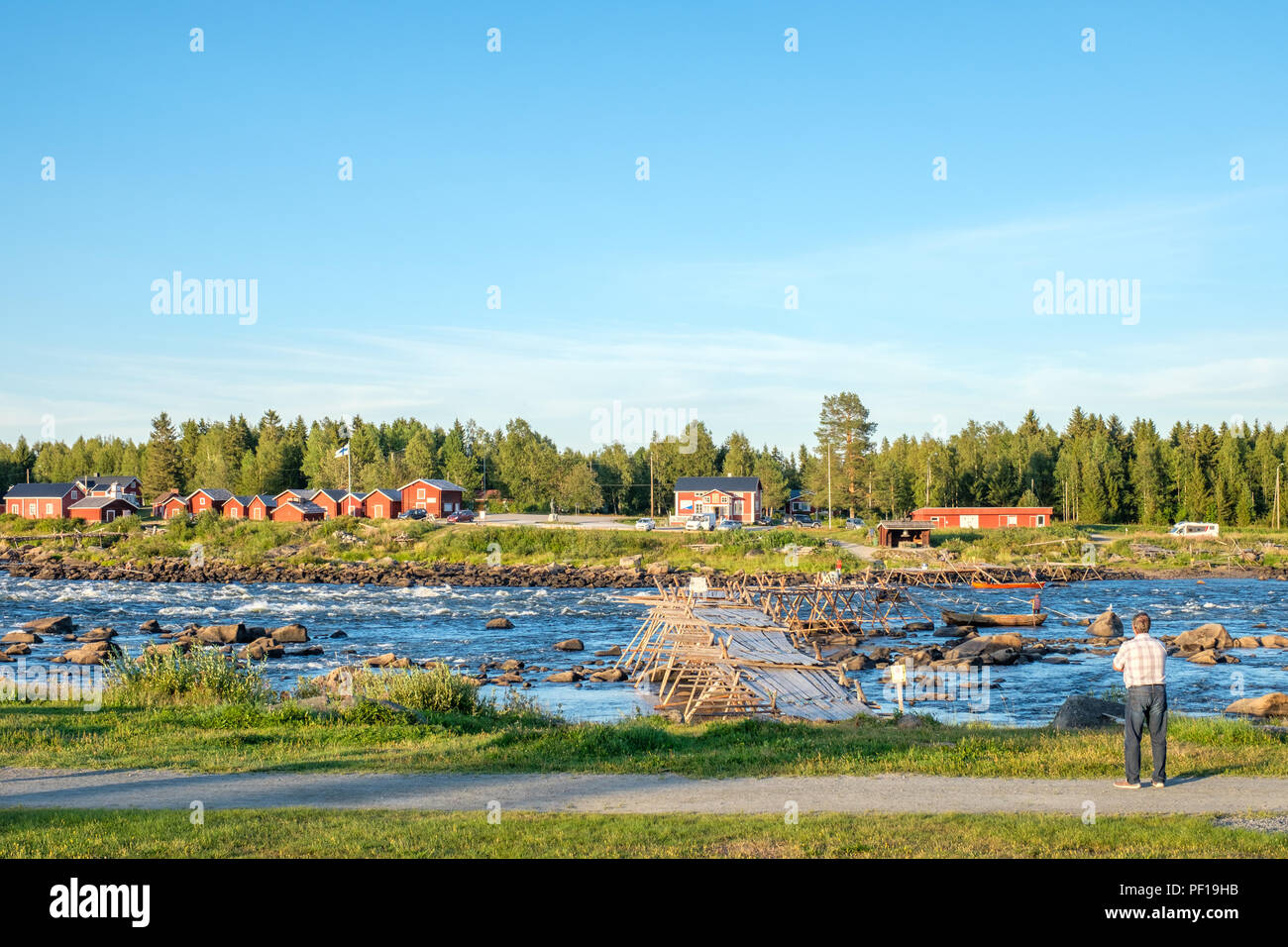 Turista gode la vista da Kukkola in Svezia attraverso il fiume Torne verso la Finlandia. Kukkola rapids è stato un sito di pesca sin dal medioevo Foto Stock