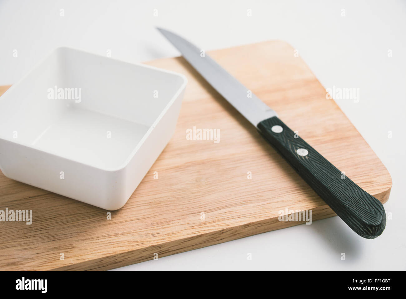 In legno blocco di trinciatura, coltello, vaso, stoviglie sul tagliere astratto sfondo alimentare Foto Stock