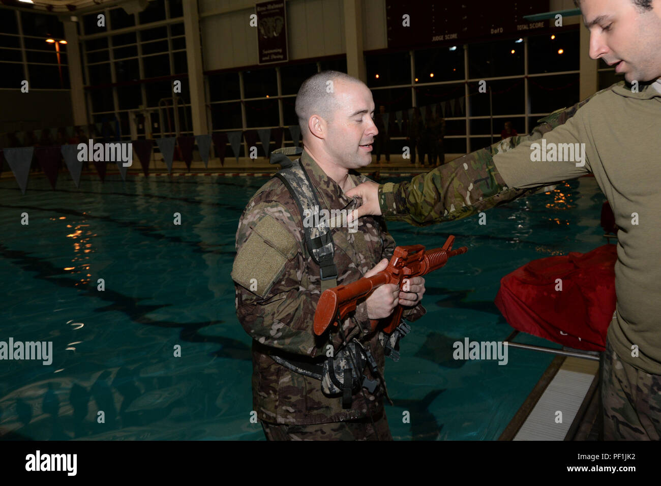 Stati Uniti Air Force aviatori assegnato all'Indiana Air National Guard, 181st ala di intelligence, 113supporto aria squadrone di funzionamento si prepara a saltare nell'acqua indossando un dispositivi di supporto del carico vest e tenendo un finto M-4 come parte della loro lotta contro la sopravvivenza dell'acqua di formazione presso il Sport e ricreazione centro del campus di Rose-Hulman Institute of Technology di Terre Haute 6 febbraio 2016. L'aviatore, dopo l'entrata in acqua, dovrebbe prendere il via il suo LBE vest per evitare di essere appesantita e prevenire l'annegamento. I membri di ASOS treno per rimanere Racer pronto. (U.S. Air National Guard foto di Airm Senior Foto Stock