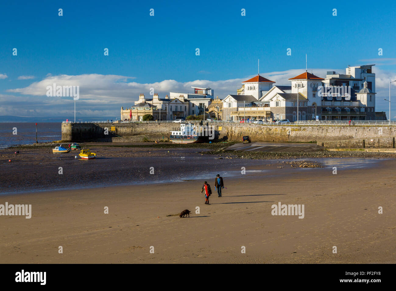 Dog walkers su una quasi deserta spiaggia di fronte Knightstone isola in inverno a Weston-super-Mare, North Somerset, Inghilterra, Regno Unito Foto Stock