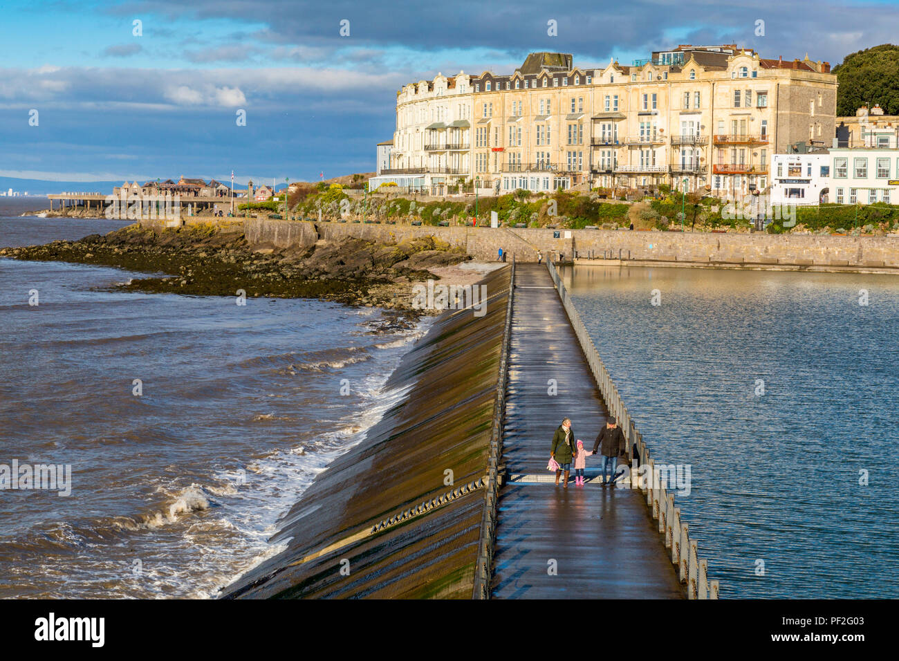 La gente camminare attraverso la parete del mare che mantiene l'acqua nel lago marino a Weston-super-Mare, North Somerset, Inghilterra, Regno Unito Foto Stock