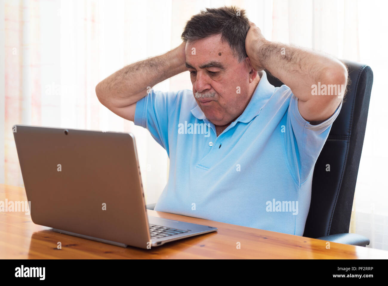 Sorpreso Senior uomo al lavoro con il computer portatile. Foto Stock