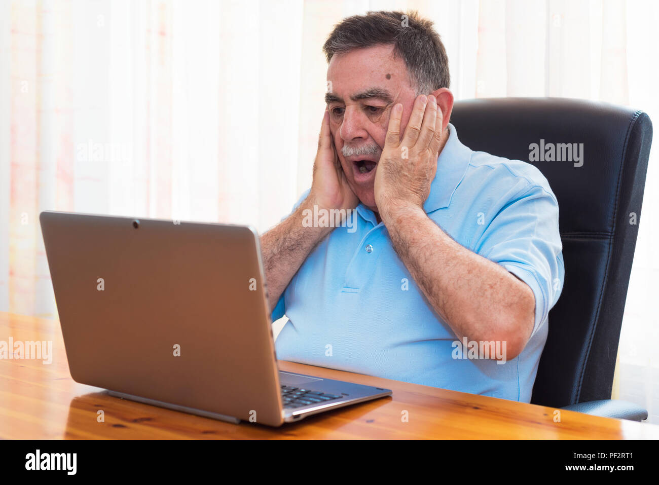 Sorpreso Senior uomo al lavoro con il computer portatile. Foto Stock
