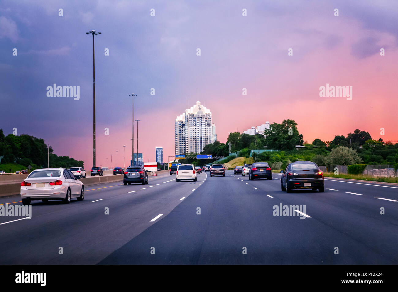 Il traffico di notte. Vetture su strada autostrada al tramonto in serata tipica occupato città americana. Bella notte incredibile vista urbano con il rosso, il giallo e il blu del cielo Foto Stock