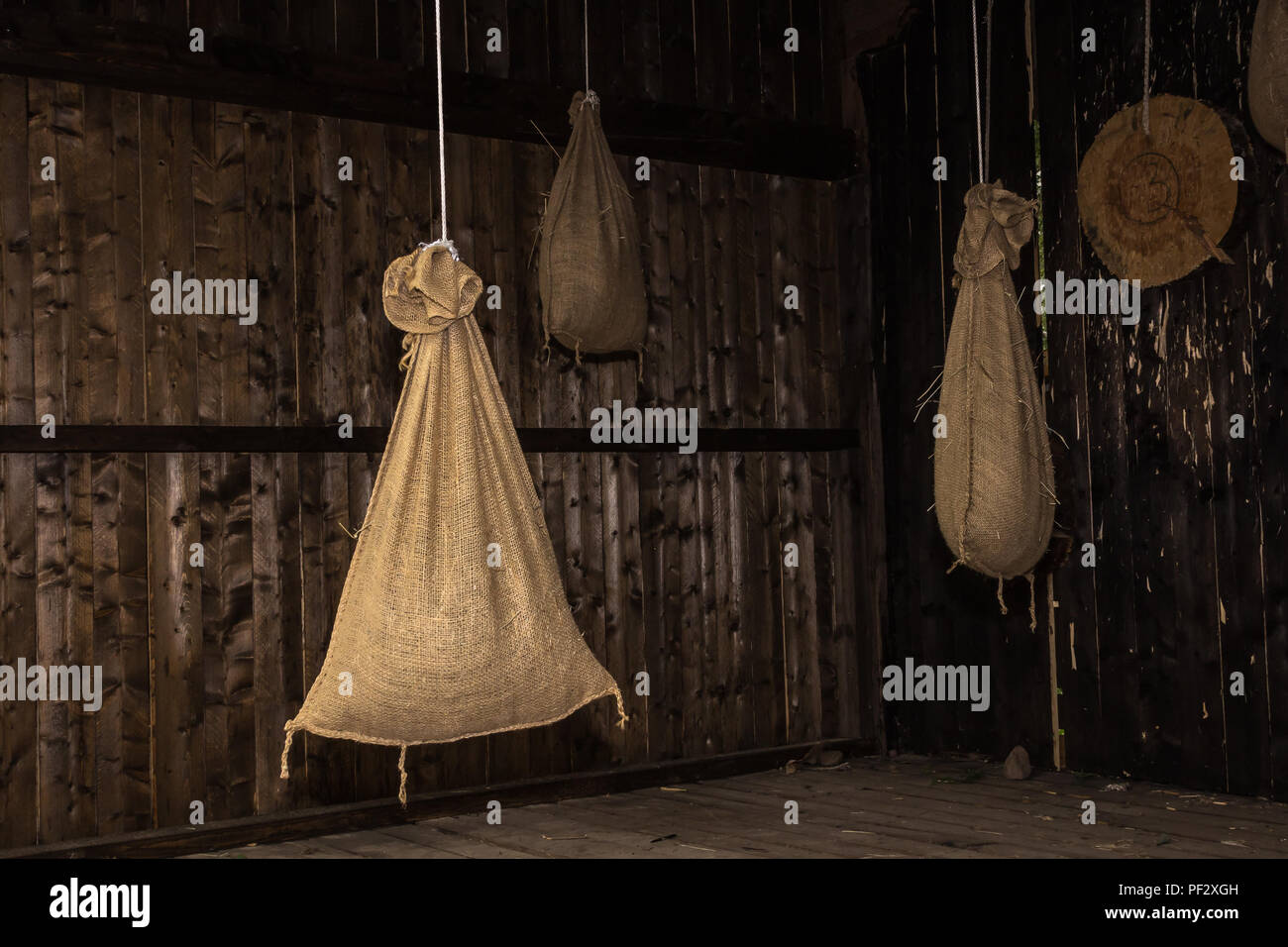 Sacchi di tessuto di iuta sono appeso a una fune in un granaio in legno Foto Stock