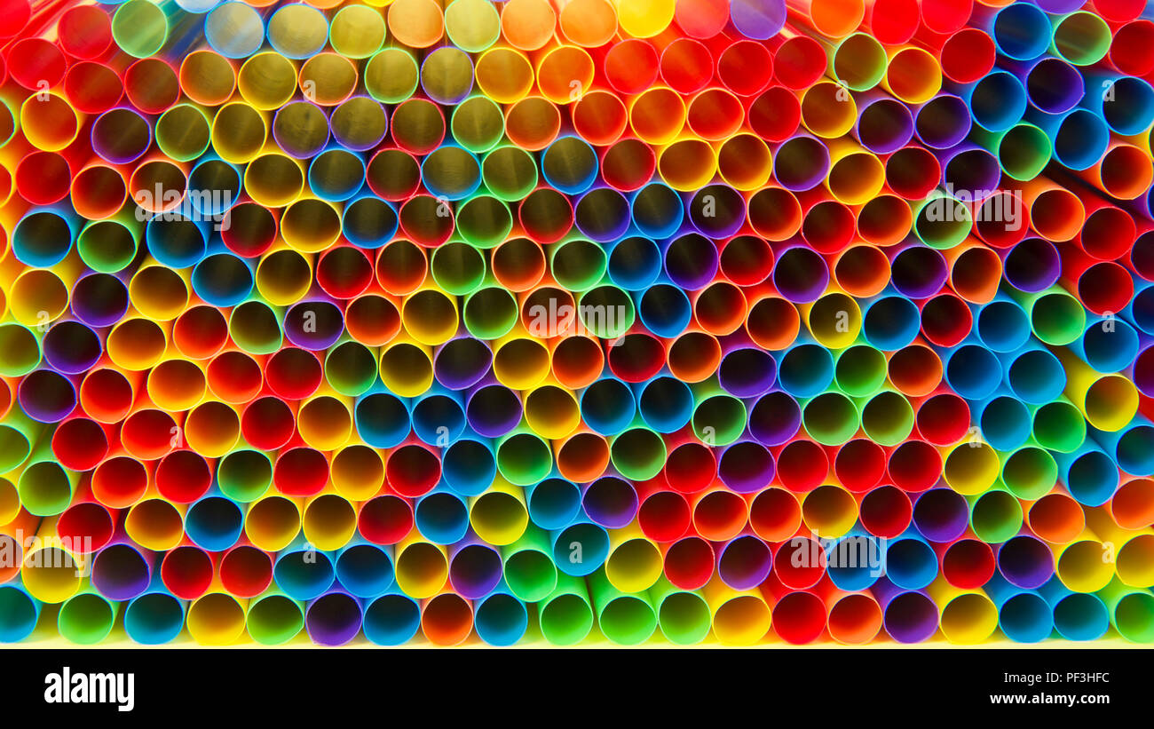 Centinaia di colorate cannucce di plastica recante rivolto in avanti verso l'apertura di viewer, posa sulla superficie gialla. Molte città sono ora il divieto di uso singola pl Foto Stock