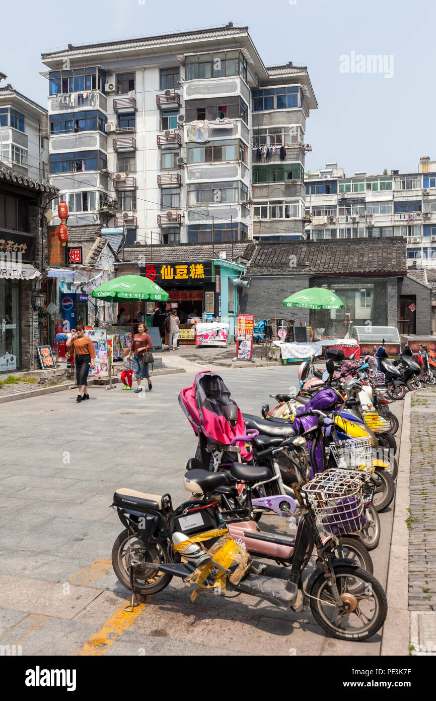 Yangzhou, Jiangsu, Cina. Motore elettrico bici, Dong Guan Street. Edifici di appartamenti in background. Foto Stock