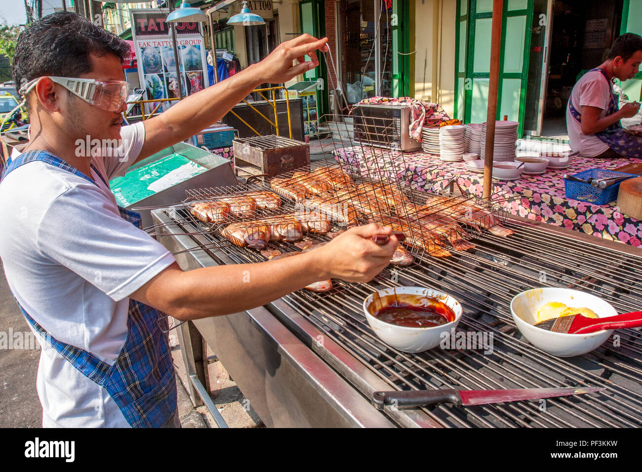 La cottura il pollo sul grill esterno in Bangok's street. Foto Stock