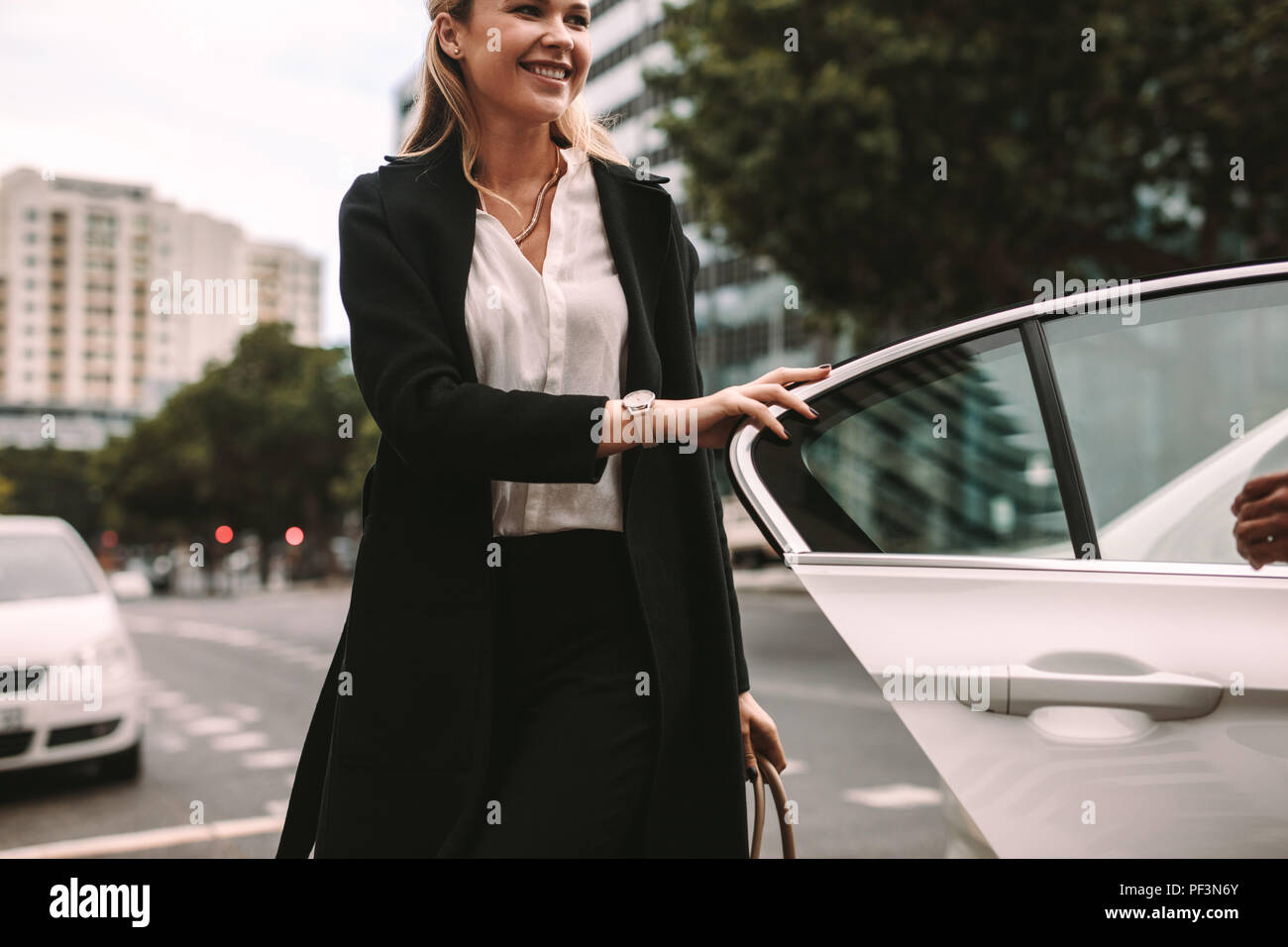 Donna sorridente commuter arrivare al di fuori di un taxi. Imprenditrice scendere una cabina. Foto Stock