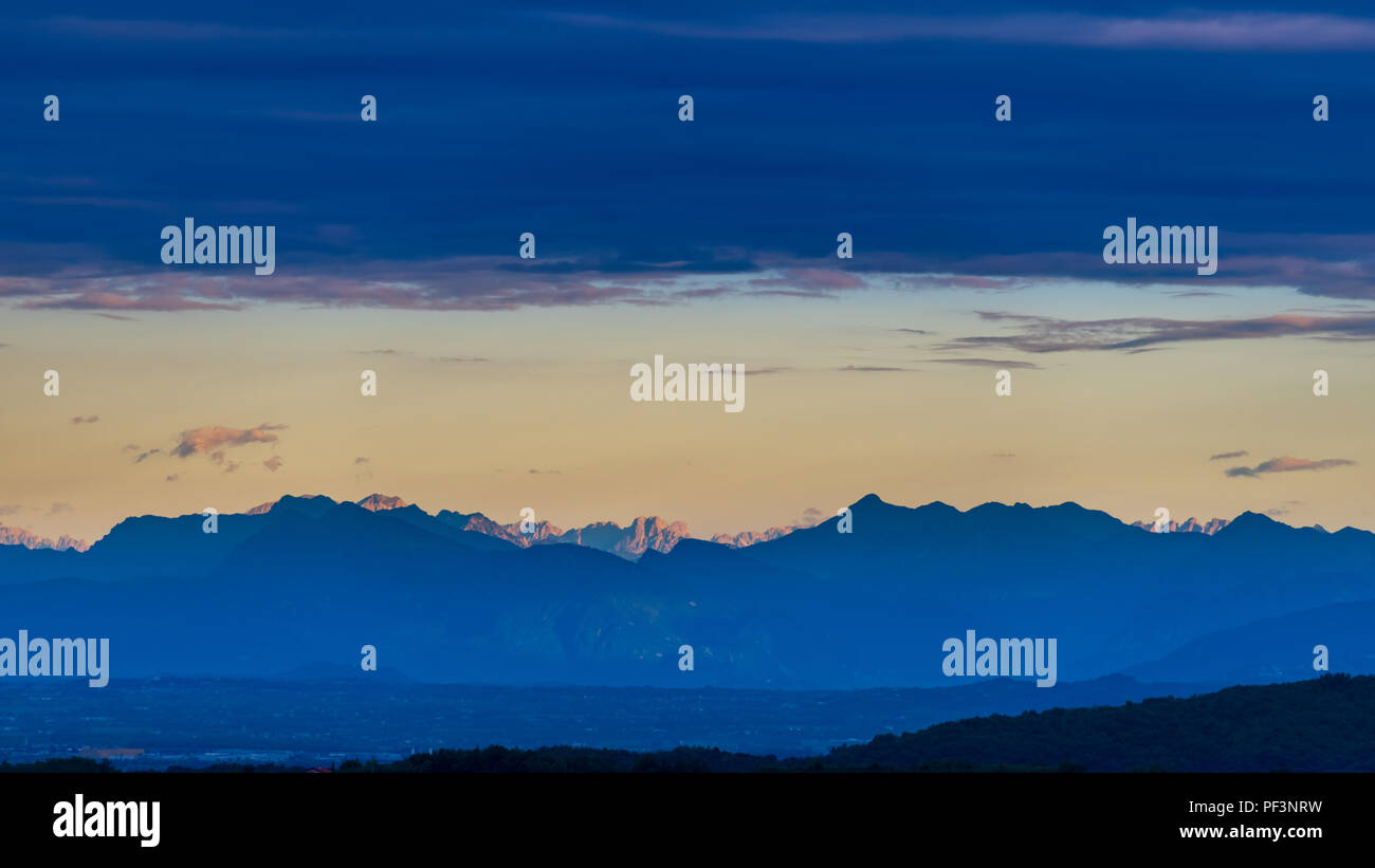 Dolomiti al mattino con nuvole sopra, i raggi del sole illuminano il più lontano dei picchi di montagna Foto Stock