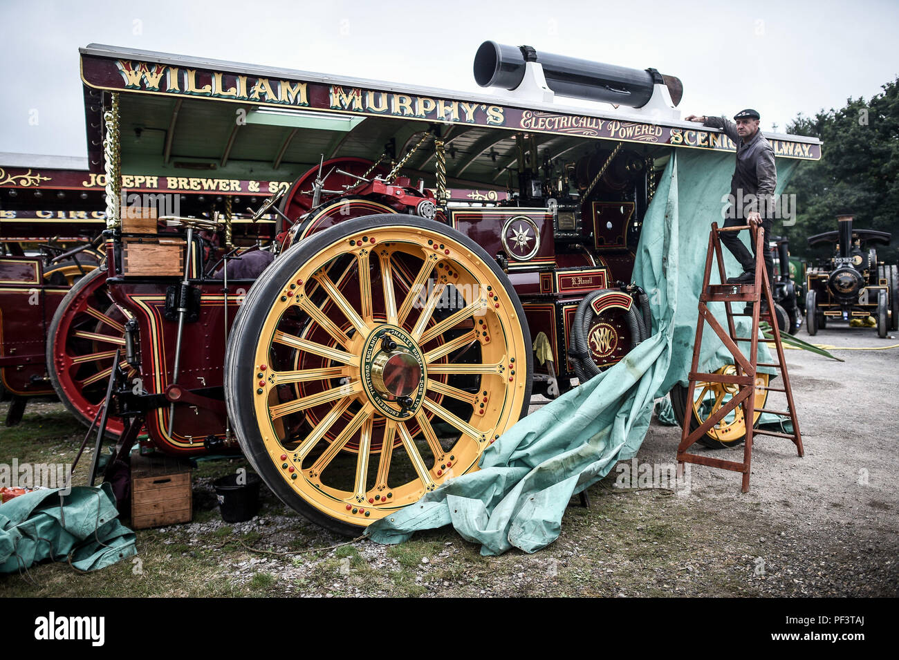 Un appassionato di vapore tiene giù un telone dal suo Burrell Showmans locomotiva stradale come dozzine di vapore veicoli alimentati a raccogliere in un pub in Dorset prima di effettuare il loro cammino verso il Grande Dorset fiera del vapore, dove centinaia di periodo i motori a trazione a vapore e pesanti attrezzature meccaniche appartenenti a tutte le epoche si riuniscono per la mostra annuale del 23 al 27 agosto 2018, per celebrare i 50 anni. Foto Stock