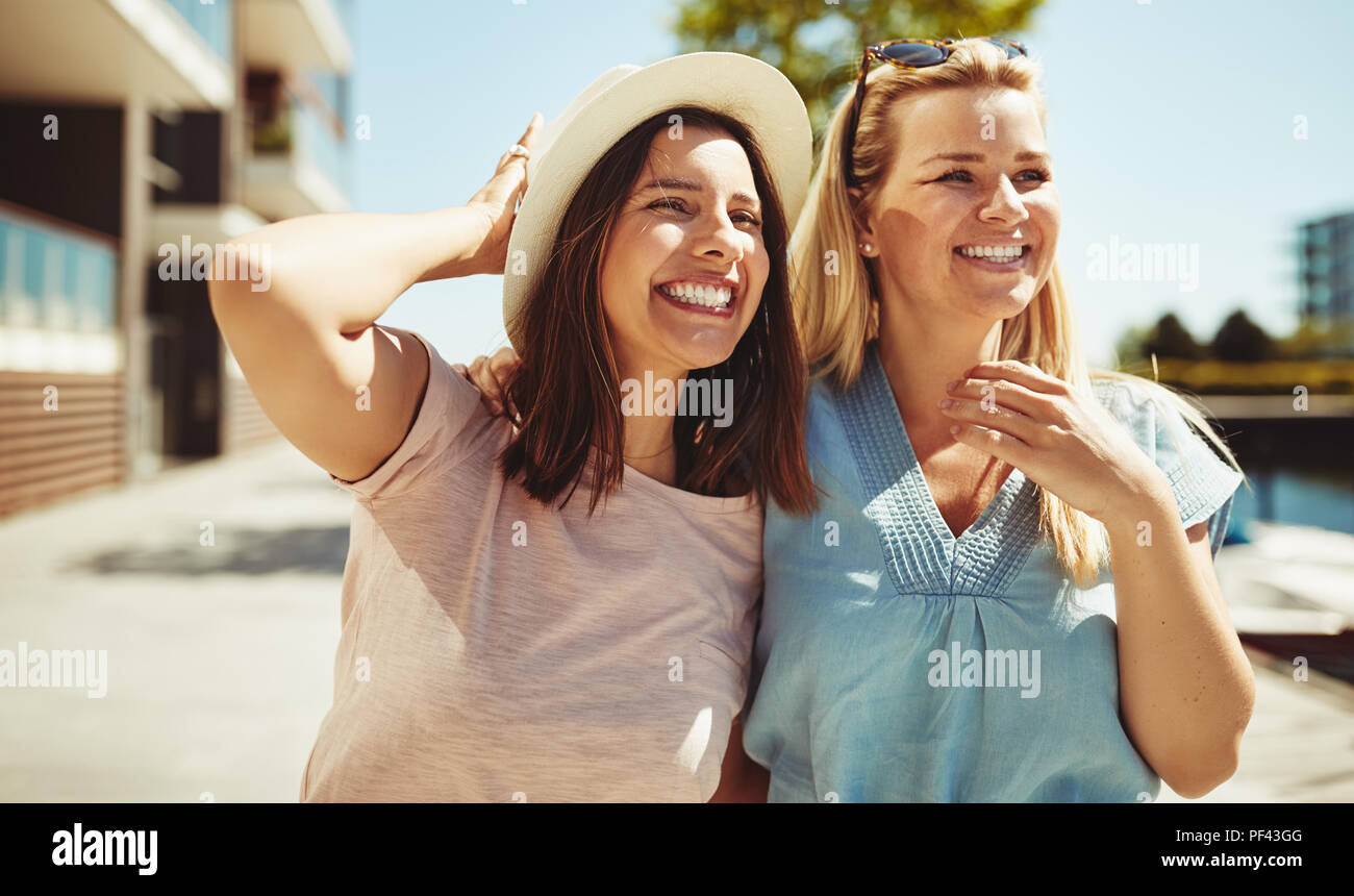 Due ridendo giovani amici di sesso femminile avente una buona volta a camminare insieme sulla giornata di sole in città Foto Stock