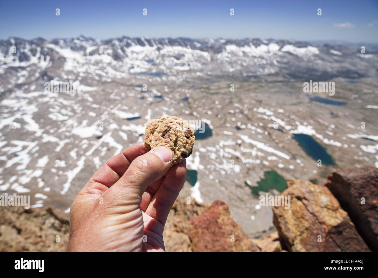 Un mans mano che tiene un Chocolate Chip Cookie sulla vetta del Monte Humphreys in Sierra Nevada della California Foto Stock