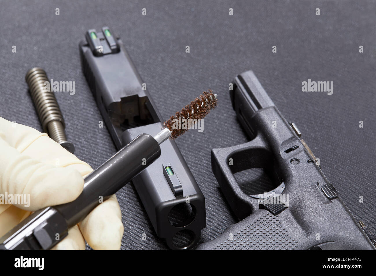 Utilizzando una spazzola per pulire le parti di una pistola con profondità di campo Foto Stock