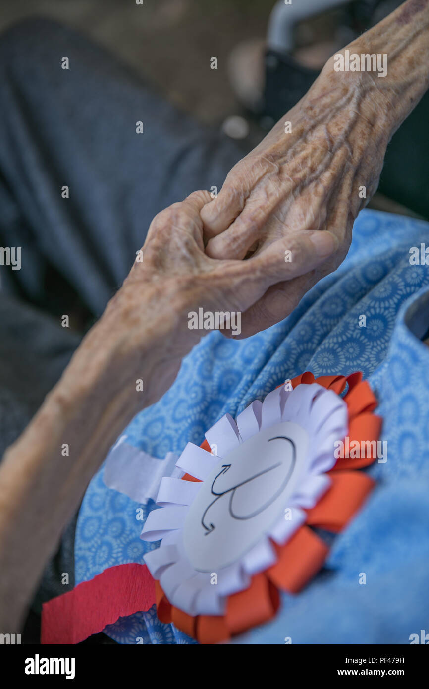 Le mani della donna anziana con il bianco e il rosso cotillion con sovrapposte emblema di ancoraggio della resistenza polacca. Anniversario dell'Insurrezione di Varsavia. Il polacco sy Foto Stock