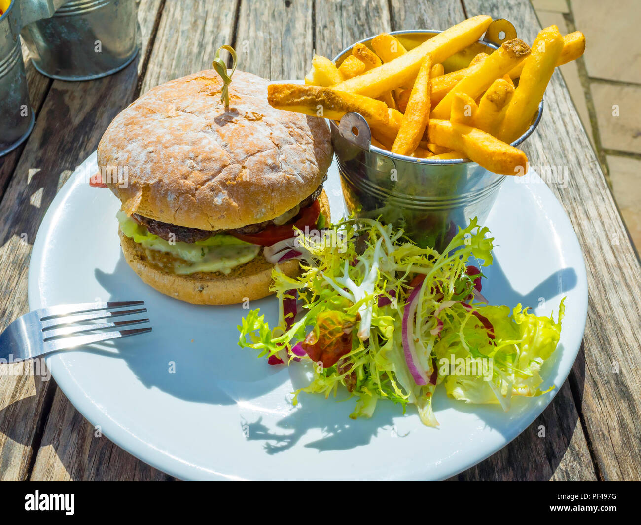CafÃ© pranzo un primo hamburger di manzo con formaggio pancetta patate fritte e insalata mista Foto Stock