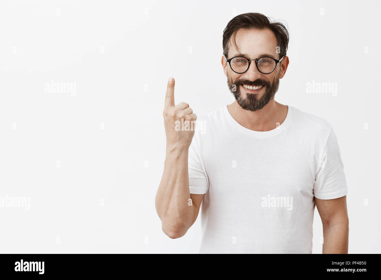 Dammi un minuto per vestire. Affascinante carefree amichevole-cerca uomo barbuto nel quartiere alla moda di occhiali, mostrando il dito indice, numering motivi perché egli ama la moglie, sorridente largamente con cura l'espressione Foto Stock