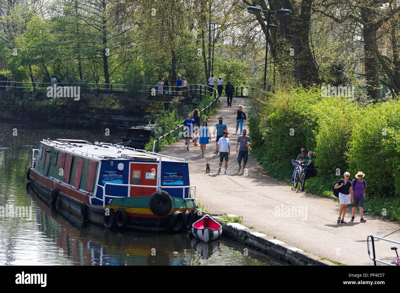 Le persone che si godono la calda giornata di primavera lungo le rive del fiume Lea in Clapton, Londra England Regno Unito Regno Unito Foto Stock