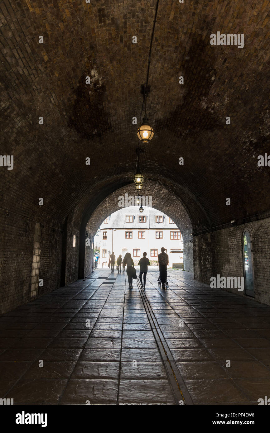 Una famiglia a piedi attraverso un tunnel scuro verso la luce all'estremità lontana. Foto Stock