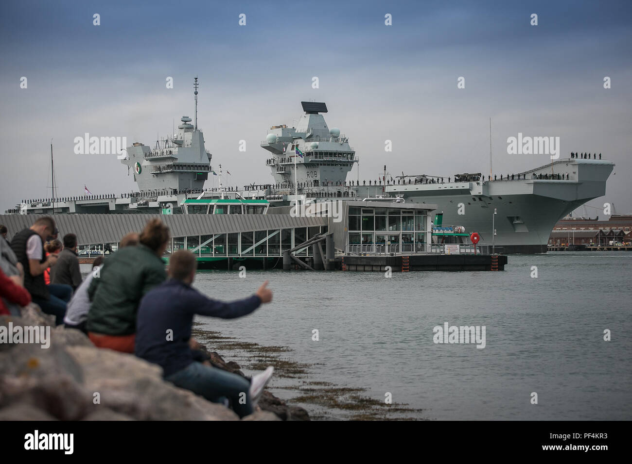 Portsmouth, Regno Unito. 18 Agosto, 2018. La Royal Navy di ultima portaerei HMS Queen Elizabeth lasciando Portsmouth Base Navale. Ella è voce negli Stati Uniti per un periodo di quattro mesi di prove in mare, un viaggio che vedrà l'introduzione dell'F35B aerei da combattimento per il suo ponte per la prima volta. Credito: David Betteridge/Alamy Live News Foto Stock