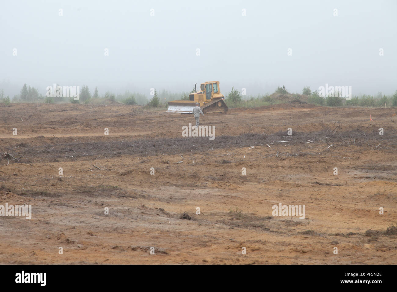 Un lone D5 Bulldozer cammina avanti e indietro, terra di livellamento nella distanza durante una distribuzione per la formazione e la costruzione di un aereo a terra nella gamma Kazlu Ruda AB, Lituania, e il agosto 16, 2018. Foto Stock