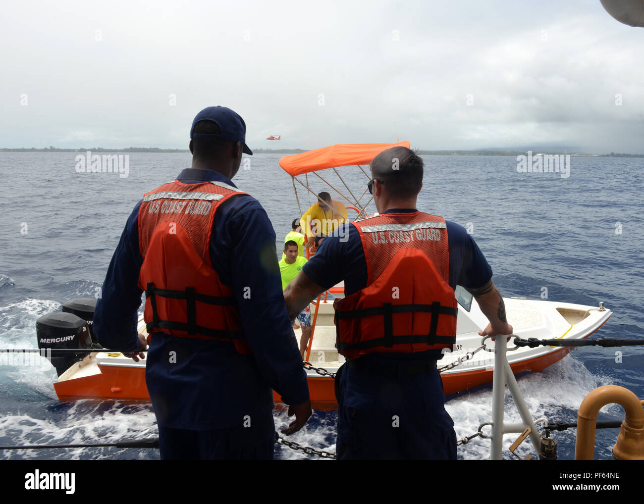 Un Hawaii County Fire Department risposta equipaggio barca tira fino a fianco dei guardacoste Oliver Berry (WPC 1124) mentre una stazione aria Barbieri Point MH-65 Delfino elicottero equipaggio si libra in background nei pressi di Hilo, Hawaii, 15 agosto 2018. La Guardia Costiera e Hawaii County sono state conducendo una ricerca ed esercitazione di soccorso per aumentare interagenzie efficacia. (U.S. Coast Guard foto di Sottufficiali di terza classe Matteo West/rilasciato) Foto Stock